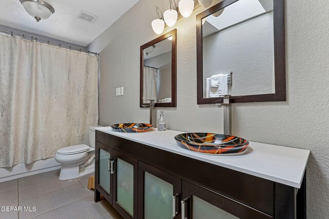 bathroom featuring toilet, vanity, tile patterned floors, and shower / tub combo with curtain