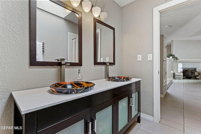 bathroom with tile patterned flooring, vanity, and a textured wall