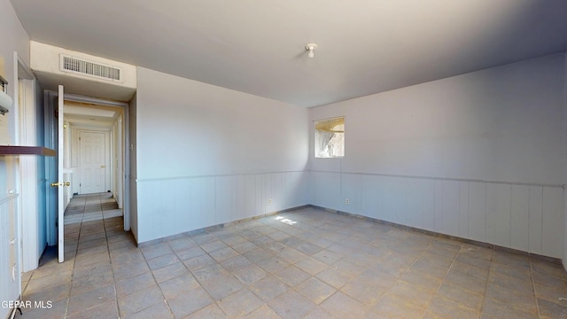 unfurnished room featuring wainscoting
