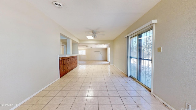 corridor with plenty of natural light, light tile patterned flooring, a textured wall, and baseboards