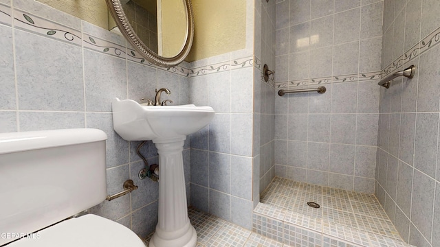 full bath featuring toilet, a stall shower, and tile walls