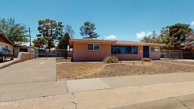 ranch-style house featuring a gate, fence, and concrete driveway