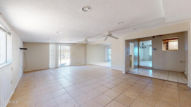 unfurnished room featuring a textured ceiling, healthy amount of natural light, light tile patterned floors, baseboards, and recessed lighting