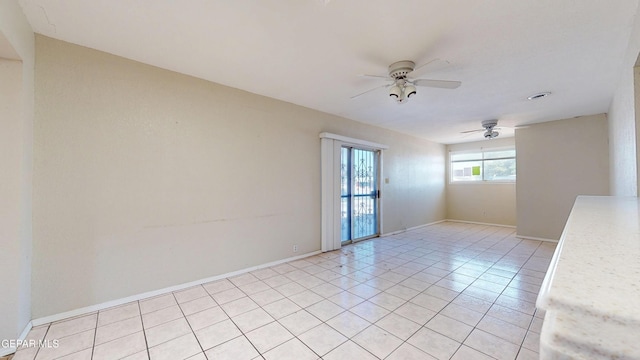 spare room featuring a ceiling fan, light tile patterned floors, and baseboards