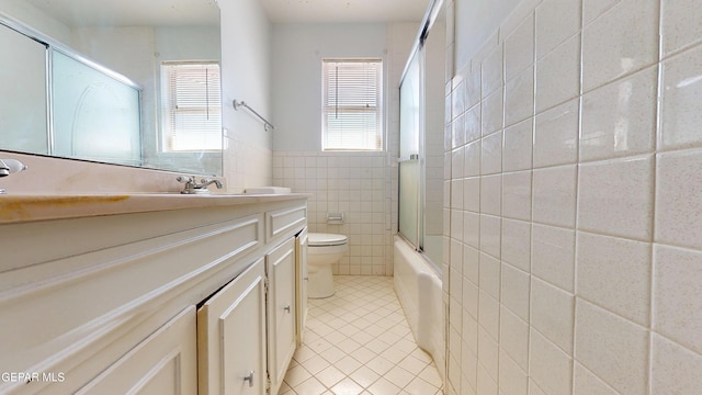 bathroom featuring tile patterned flooring, tile walls, toilet, vanity, and enclosed tub / shower combo