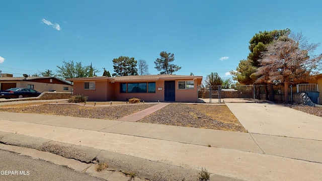 ranch-style home with concrete driveway, a gate, and fence