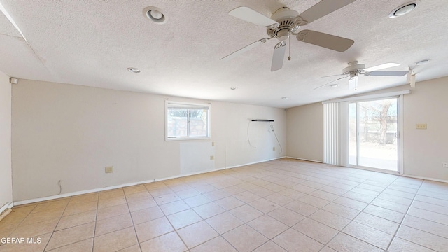 unfurnished room featuring a textured ceiling, a ceiling fan, light tile patterned floors, and baseboards
