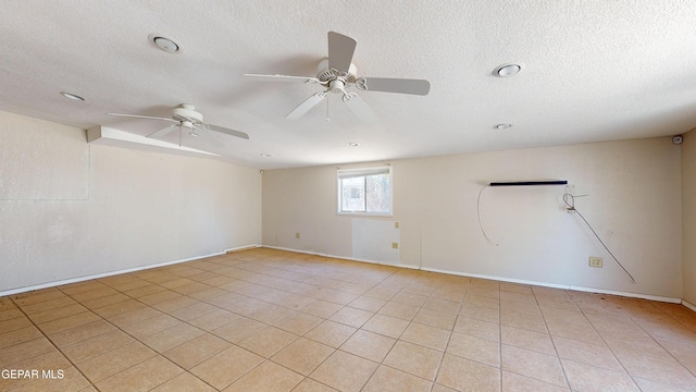 spare room with a textured ceiling, a ceiling fan, light tile patterned flooring, and baseboards