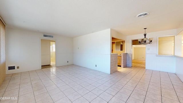 empty room with a chandelier and light tile patterned flooring