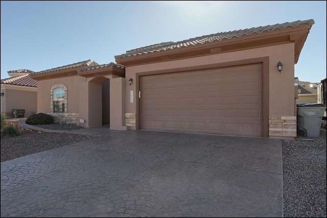 view of front facade with stucco siding, driveway, a tiled roof, and a garage