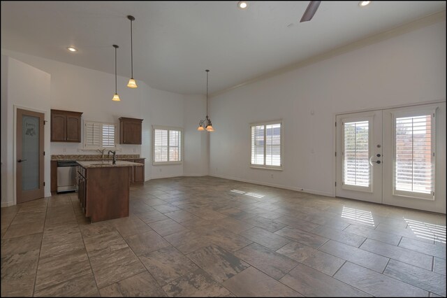 kitchen with dishwasher, a center island with sink, high vaulted ceiling, open floor plan, and baseboards