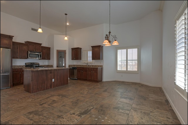 kitchen with stainless steel appliances, high vaulted ceiling, a sink, healthy amount of natural light, and a chandelier