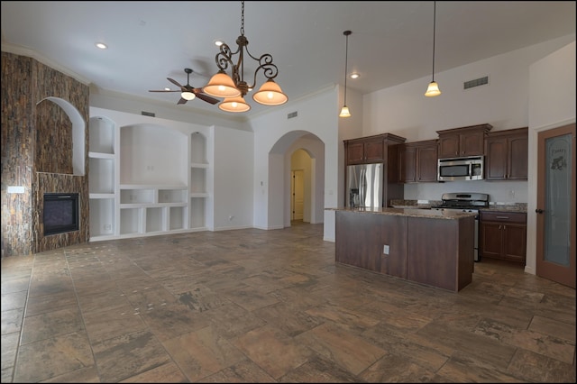 kitchen with appliances with stainless steel finishes, built in shelves, open floor plan, a kitchen island, and ceiling fan