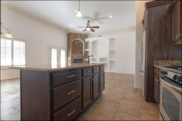 kitchen featuring gas range, a ceiling fan, a sink, built in shelves, and dark brown cabinets