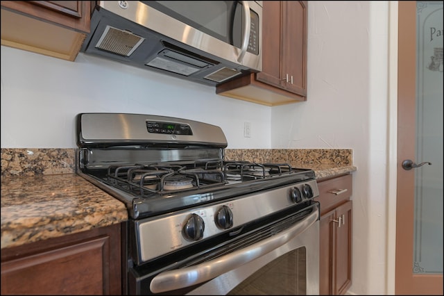 kitchen featuring stainless steel appliances and dark stone countertops