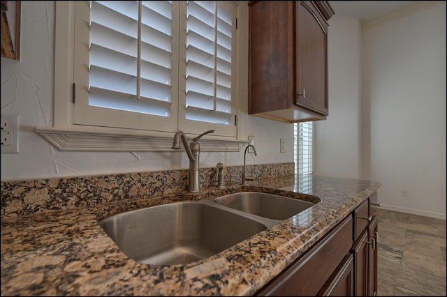 kitchen featuring a sink, dark stone counters, dark brown cabinets, and decorative backsplash