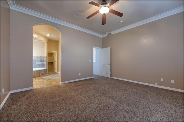 empty room featuring crown molding, a ceiling fan, arched walkways, carpet floors, and baseboards