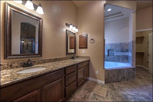 full bathroom with baseboards, tiled tub, and double vanity