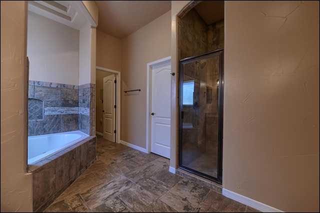 bathroom with a stall shower, a garden tub, and baseboards