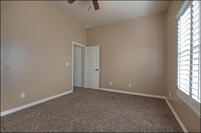 carpeted spare room with ceiling fan, plenty of natural light, and baseboards