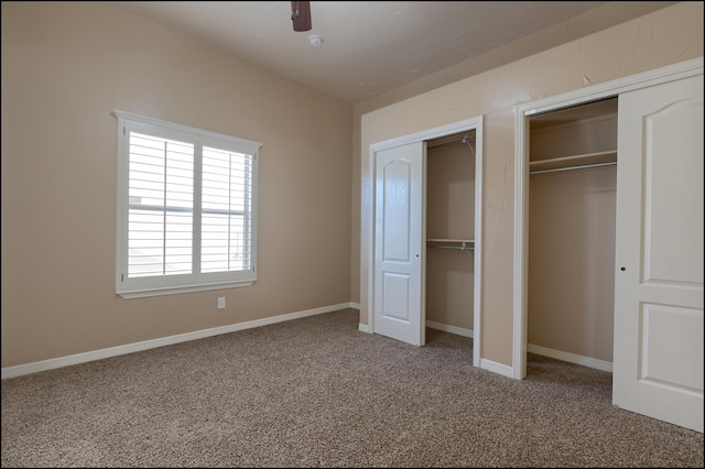 unfurnished bedroom with two closets, carpet, and baseboards