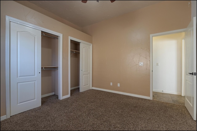 unfurnished bedroom featuring multiple closets, carpet flooring, and baseboards