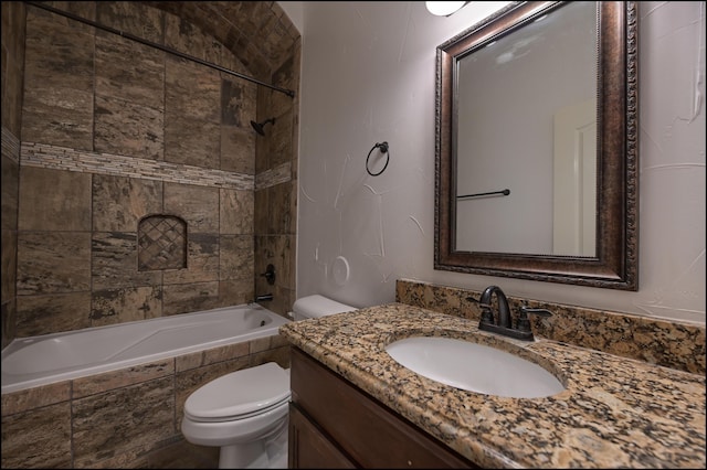bathroom featuring toilet, vanity, and tiled shower / bath