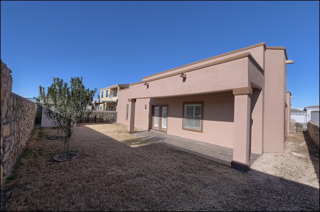 back of house with stucco siding, a fenced backyard, and a patio