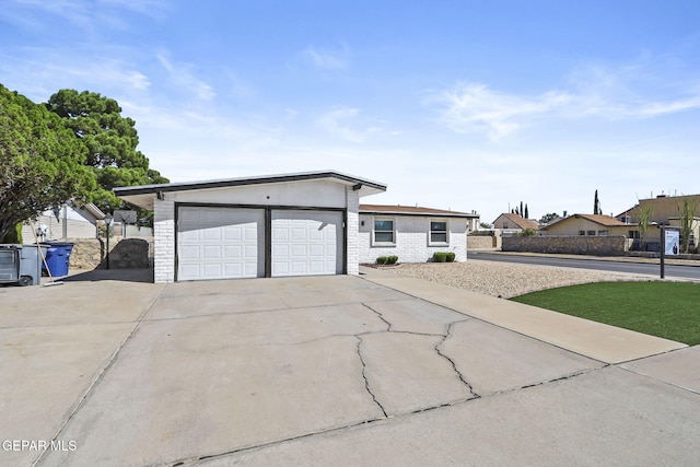 ranch-style home featuring driveway, fence, and an attached garage