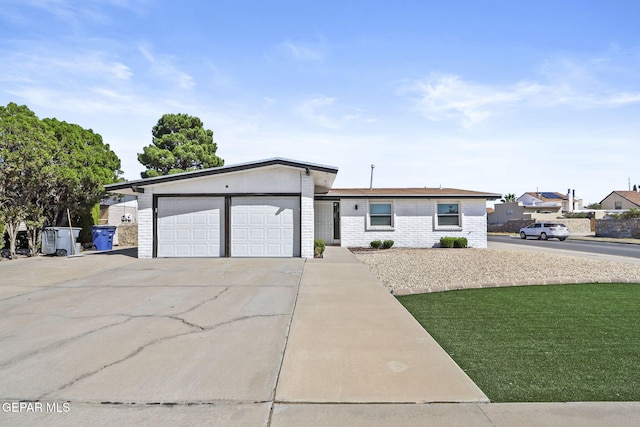 ranch-style house featuring concrete driveway, an attached garage, brick siding, and a front lawn