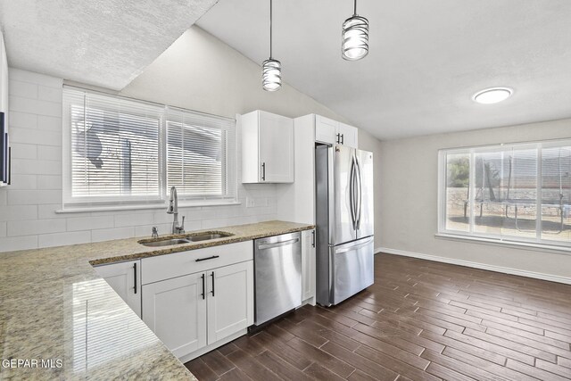 kitchen featuring appliances with stainless steel finishes, a sink, baseboards, white cabinets, and tasteful backsplash
