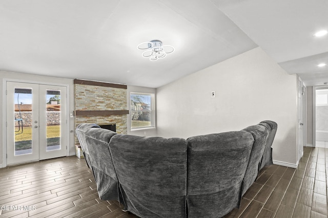 living area with wood finish floors, french doors, baseboards, a stone fireplace, and recessed lighting