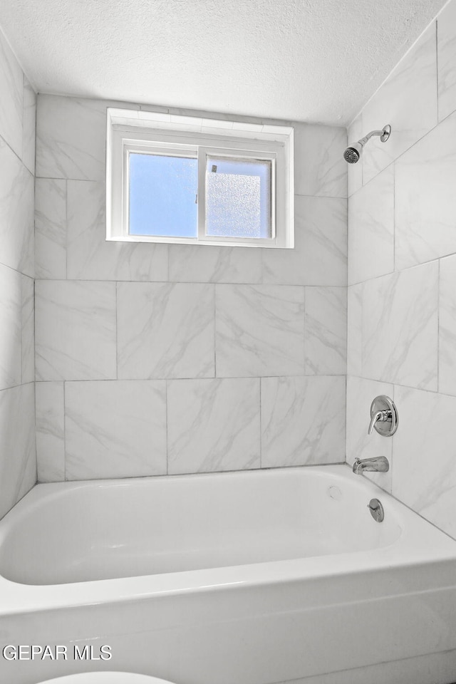 bathroom featuring a textured ceiling, healthy amount of natural light, and shower / bathtub combination