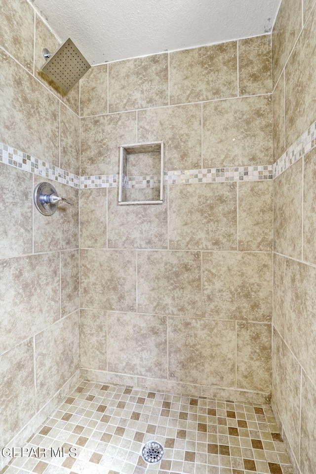 bathroom featuring a tile shower and a textured ceiling