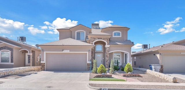 mediterranean / spanish house featuring stucco siding, stone siding, and concrete driveway
