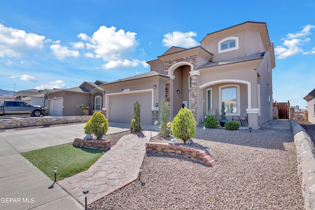 mediterranean / spanish home featuring stucco siding, concrete driveway, an attached garage, and stone siding
