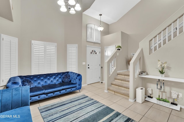 tiled entrance foyer featuring a towering ceiling, stairway, baseboards, and a chandelier