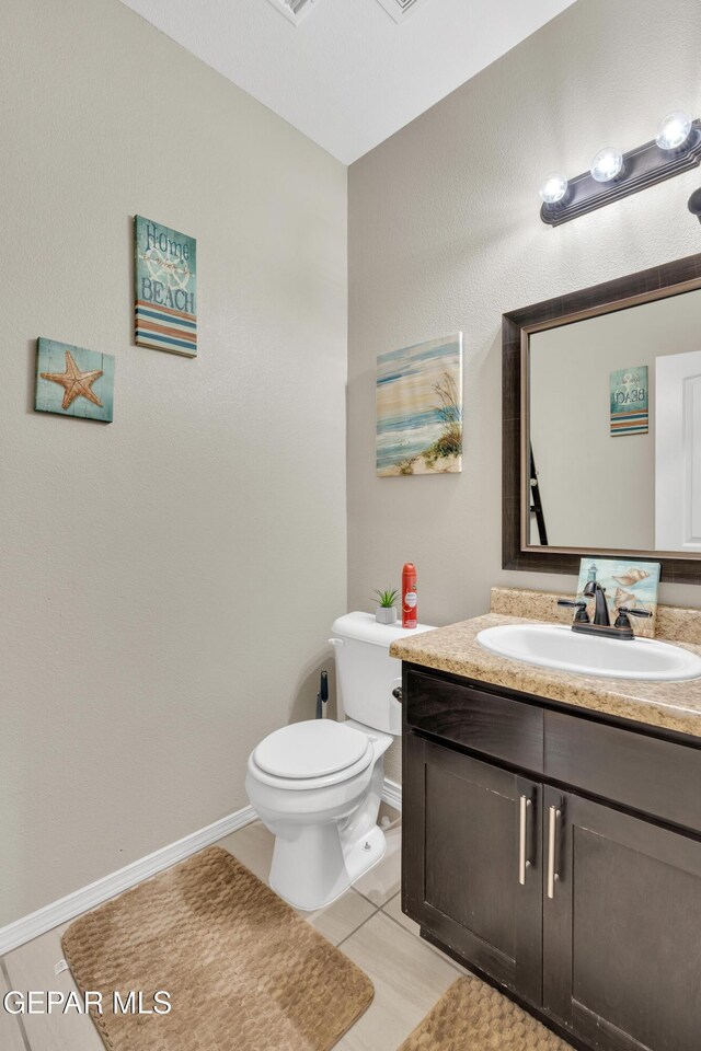 bathroom with baseboards, toilet, vanity, and tile patterned floors