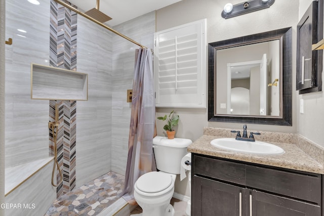 full bathroom featuring a tile shower, vanity, and toilet