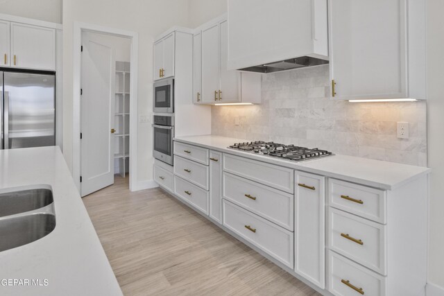 820 Acton St, Horizon City, TX 79928 - kitchen featuring stainless steel appliances, white cabinets, light countertops, decorative backsplash, and light wood finished floors