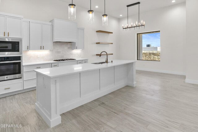 820 Acton St, Horizon City, TX 79928 - kitchen featuring oven, a sink, built in microwave, light countertops, and a center island with sink