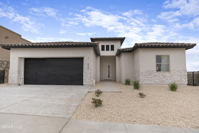 820 Acton St, Horizon City, TX 79928 - mediterranean / spanish home featuring driveway, stone siding, stucco siding, a garage, and a tiled roof