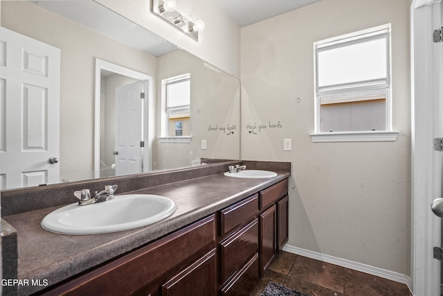 full bathroom with baseboards and double vanity