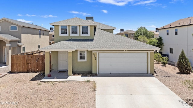 traditional-style home featuring a shingled roof, fence, driveway, an attached garage, and stucco siding