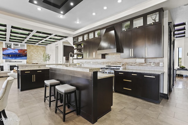 5905 Ojo De Agua Dr, El Paso, TX 79912 - kitchen with wall chimney range hood, a center island with sink, backsplash, coffered ceiling, and a kitchen bar