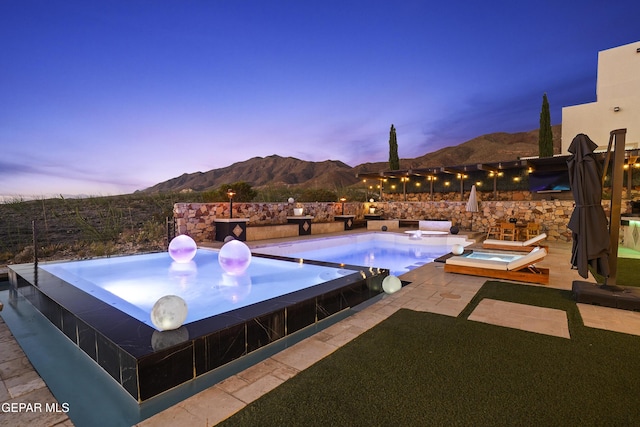 5905 Ojo De Agua Dr, El Paso, TX 79912 - pool at dusk featuring an in-ground hot tub, a mountain view, and a patio area