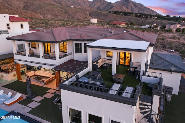5905 Ojo De Agua Dr, El Paso, TX 79912 - back of house at dusk featuring an outdoor living space, a balcony, a mountain view, and a patio