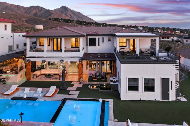 5905 Ojo De Agua Dr, El Paso, TX 79912 - rear view of house featuring a balcony, outdoor lounge area, a mountain view, stucco siding, and a lawn