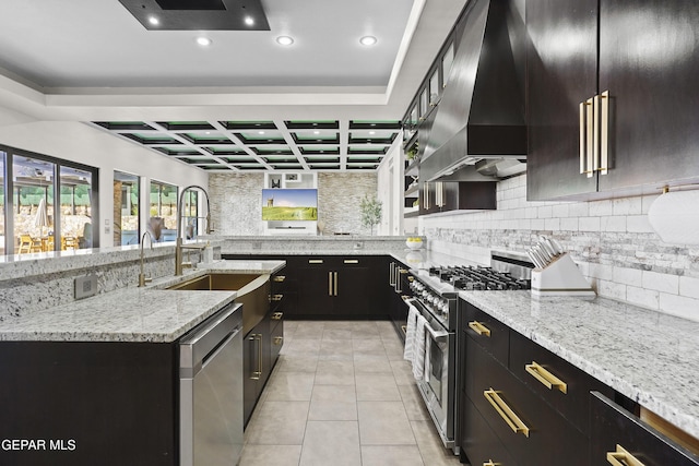 5905 Ojo De Agua Dr, El Paso, TX 79912 - kitchen featuring appliances with stainless steel finishes, coffered ceiling, wall chimney range hood, backsplash, and recessed lighting
