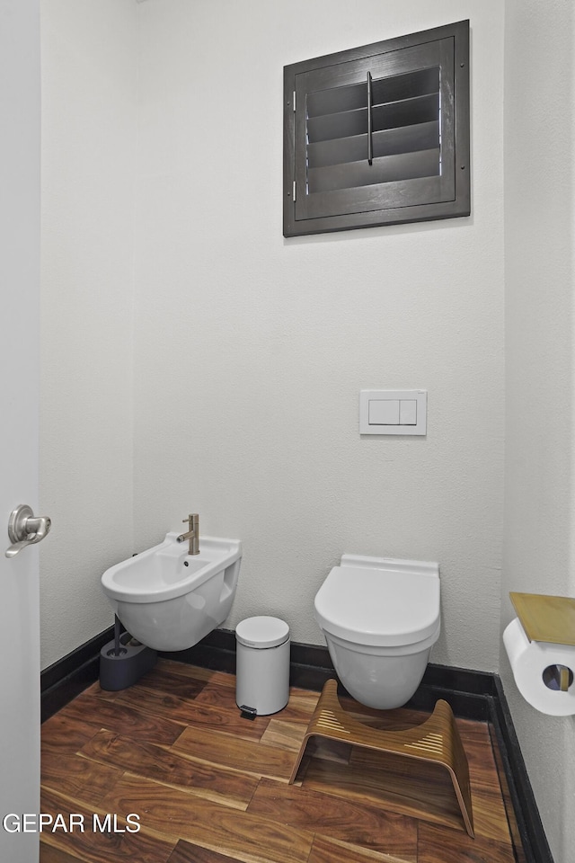 5905 Ojo De Agua Dr, El Paso, TX 79912 - bathroom with a bidet, toilet, baseboards, and wood finished floors